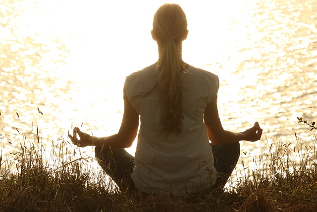 Woman meditating in front of lake in sunrise