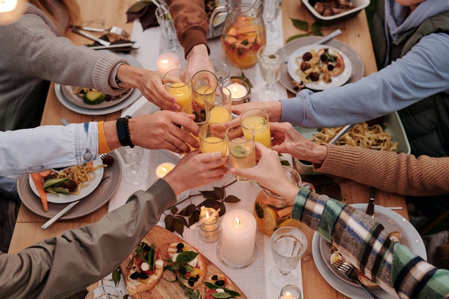 A dinner with seven people toasting with orange jusice