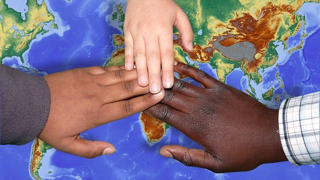 three hand of different people put together on a world map