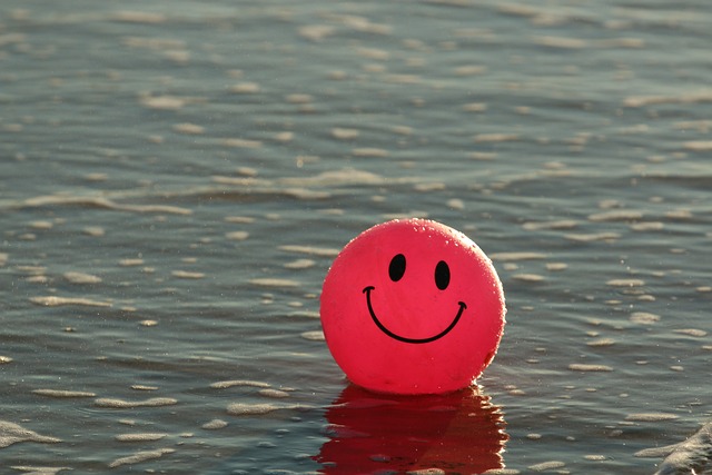 A red ballon with a smiley face floating on a lake
