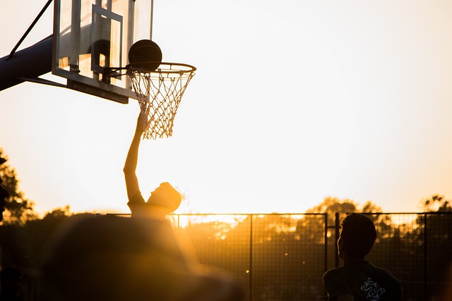 A silhouette of a man playing basketball in the sunset